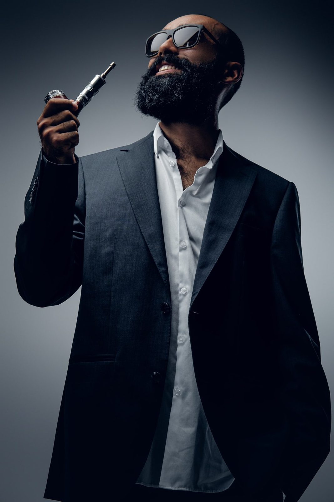 Portrait studio d’un homme barbu en costume et lunettes de soleil